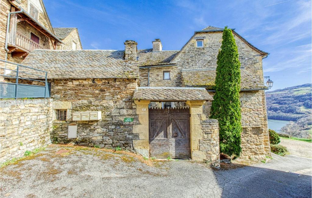 an old stone house with a large wooden door at Cozy Home In Castelnau D Mandailles With Kitchen in Castelnau-de-Mandailles