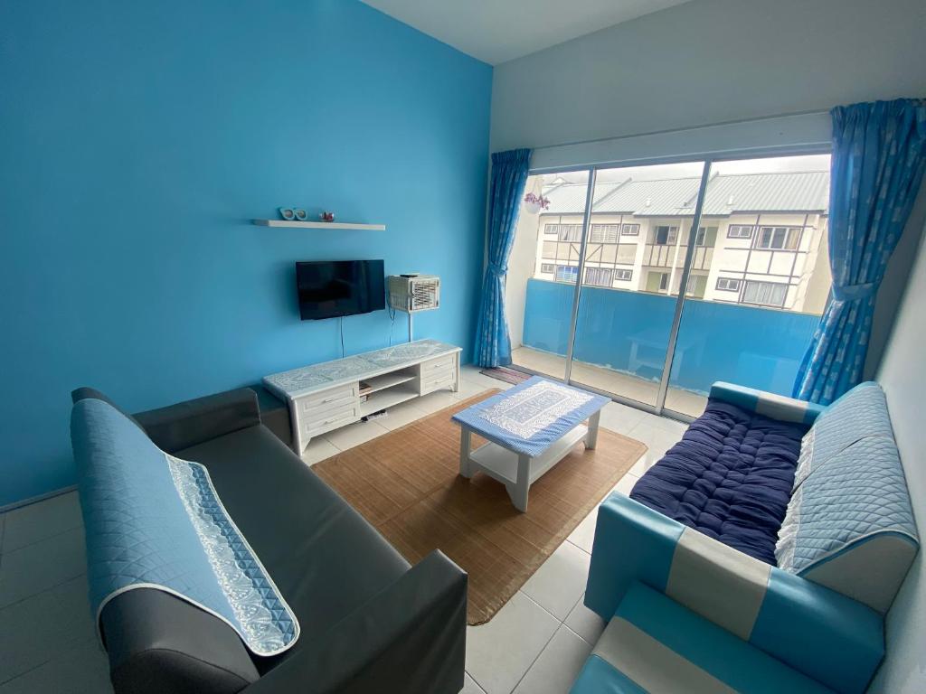 a blue living room with a couch and a tv at The Sky - The Cave Guest House in Tanah Rata