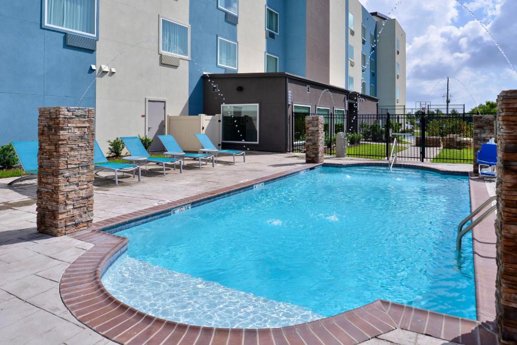 a large swimming pool with chairs and a building at TownePlace Suites by Marriott Laplace in Laplace