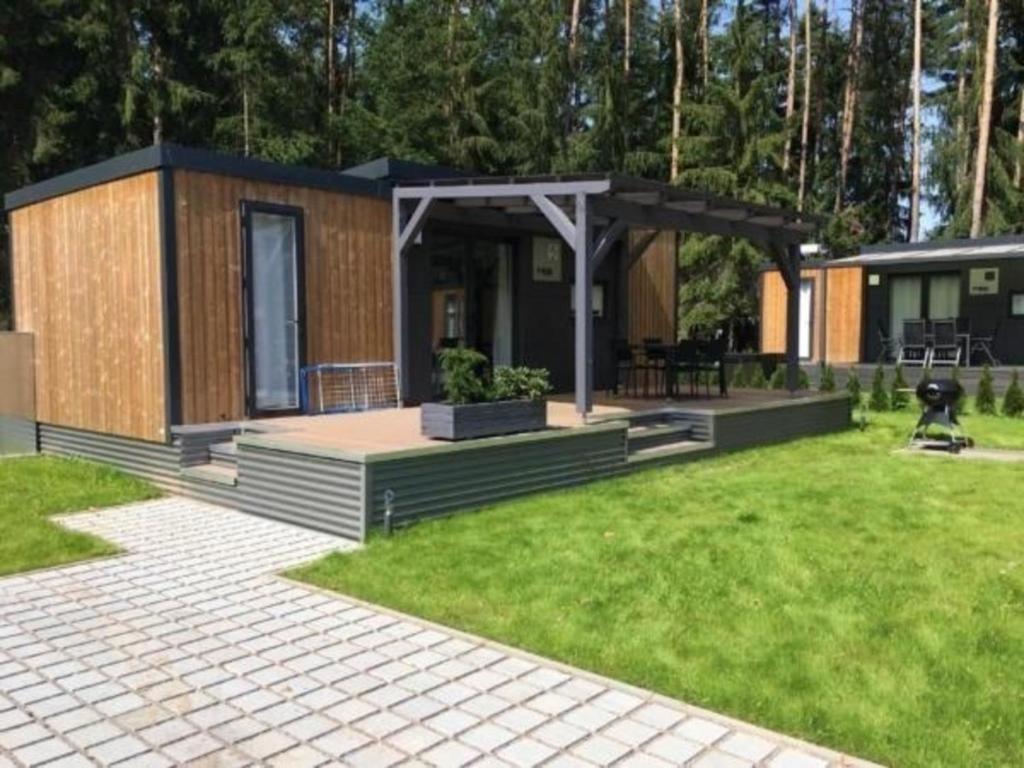 eine kleine Hütte mit einer Veranda im Hof in der Unterkunft Modernes Mobilheim am See mit Fass-Sauna und Whirlpool WA104 in Wackersdorf