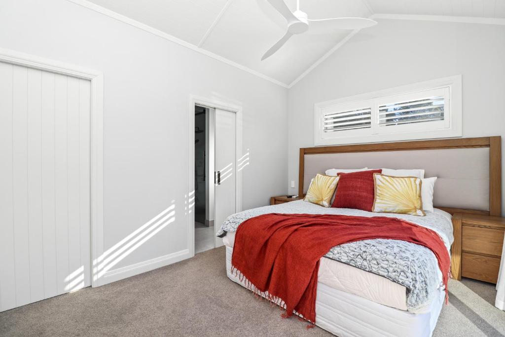 a white bedroom with a bed with a red blanket at Sanctuary Ridge in Tauranga
