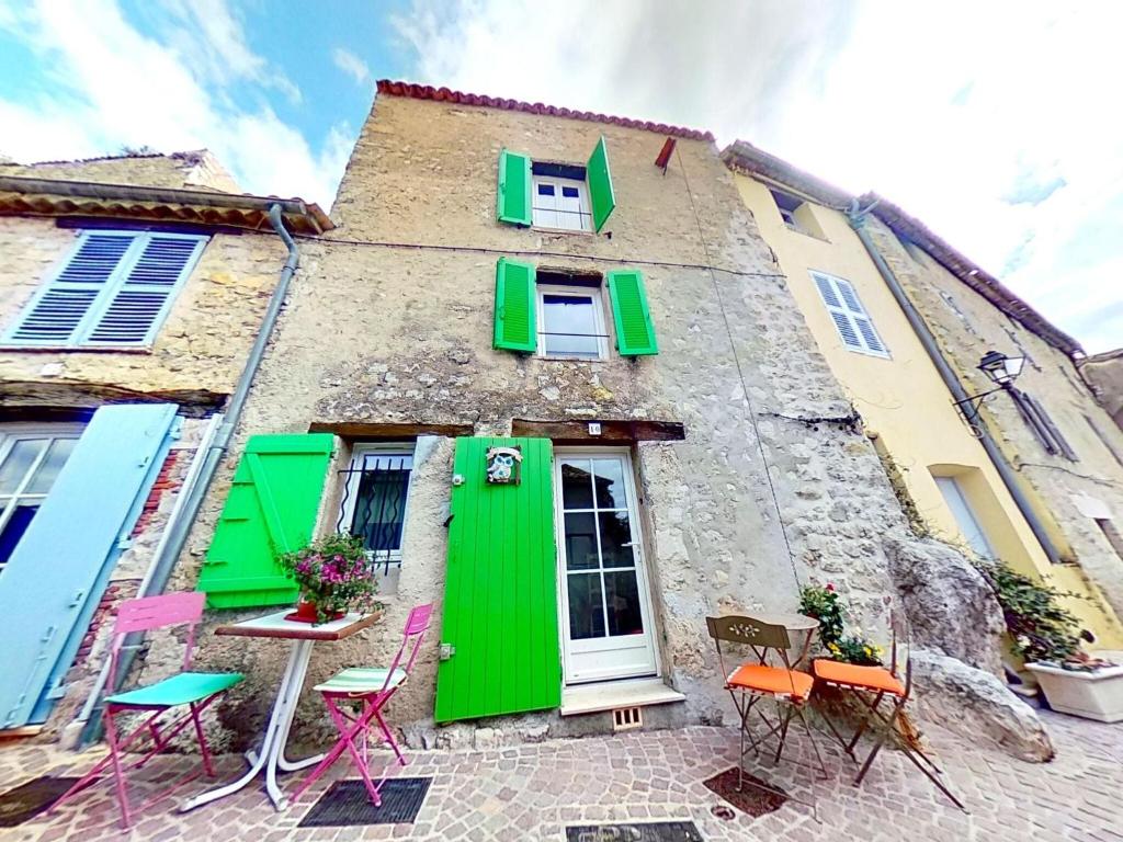 a building with green doors and chairs in front of it at Sunny house in Fayence with terrace in Fayence