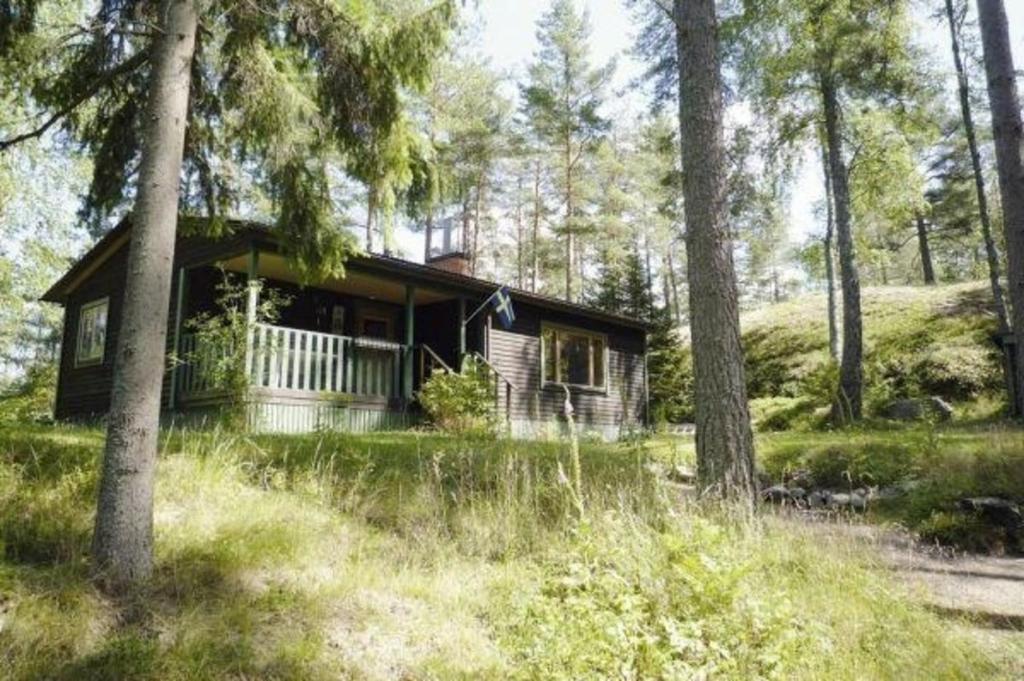 una pequeña cabaña en el bosque con árboles en Ruhig gelegenes Holzhütte mit Terrasse inmitten eines Waldgebiets in der Nähe eines Sees en Flen