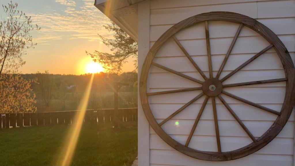 a wooden wagon wheel on the side of a house with the sunset at La Roue Dort in Saint-Raymond