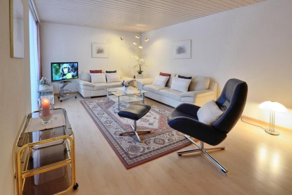 - un salon avec un canapé, des chaises et une télévision dans l'établissement Apartment Skyline 108, à Saint-Moritz