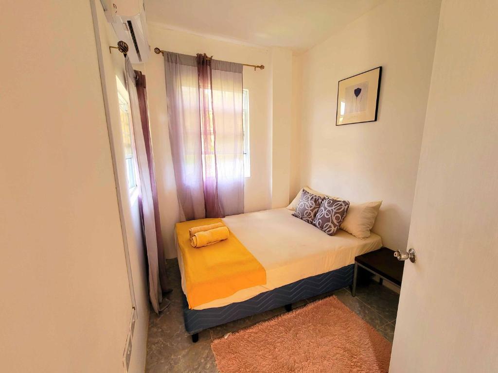 ein kleines Bett in einem kleinen Zimmer mit Fenster in der Unterkunft Comfort Suites - Two Bedroom Apartment in Choiseul