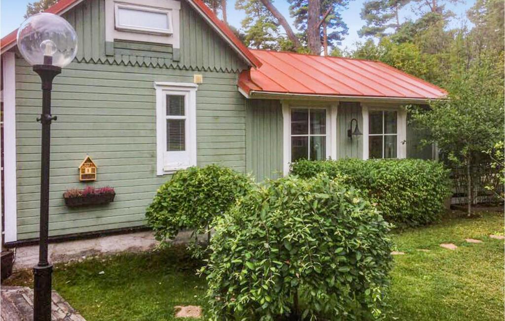 une maison verte avec un toit rouge et un éclairage de rue dans l'établissement Cozy Home In Stavsns With Wifi, à Djurhamn