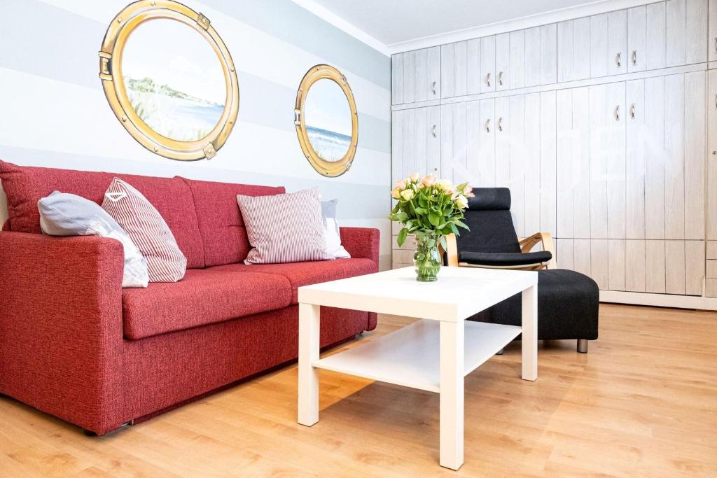 - un salon avec un canapé rouge et une table blanche dans l'établissement Andreas-Dirks-Str-1-2-OG-Wohnung-207, à Westerland