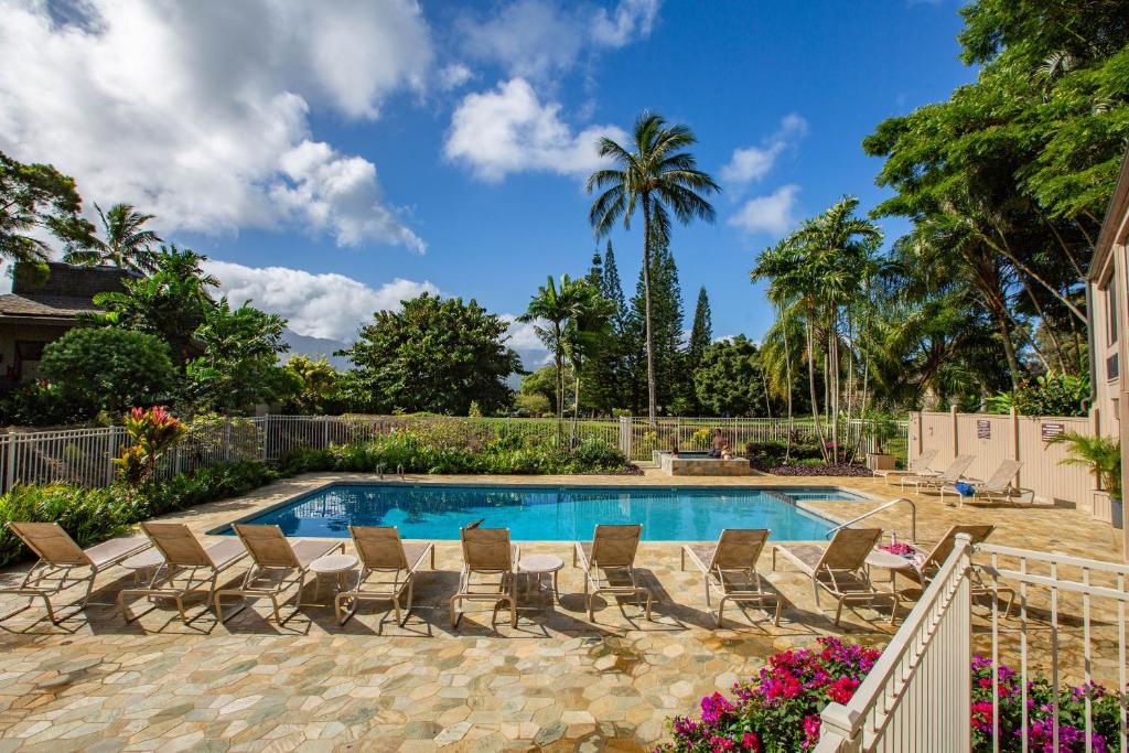 a swimming pool with chairs and a palm tree at Pali Ke Kua 207 in Princeville