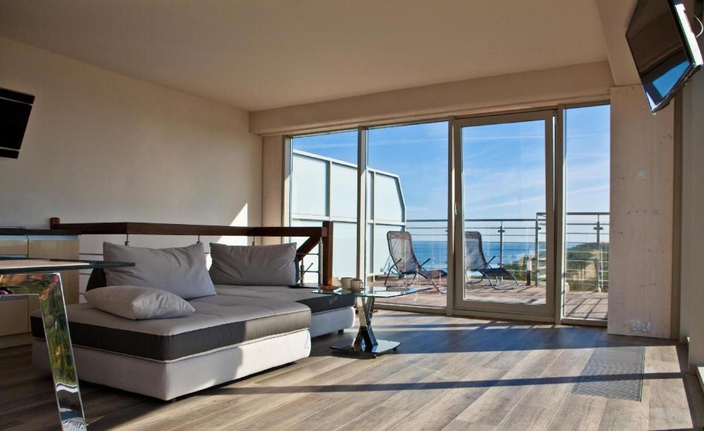 een woonkamer met een bank en uitzicht op de oceaan bij Wohnung mit Panoramaverglasung und Meerblick in Dziwnówek