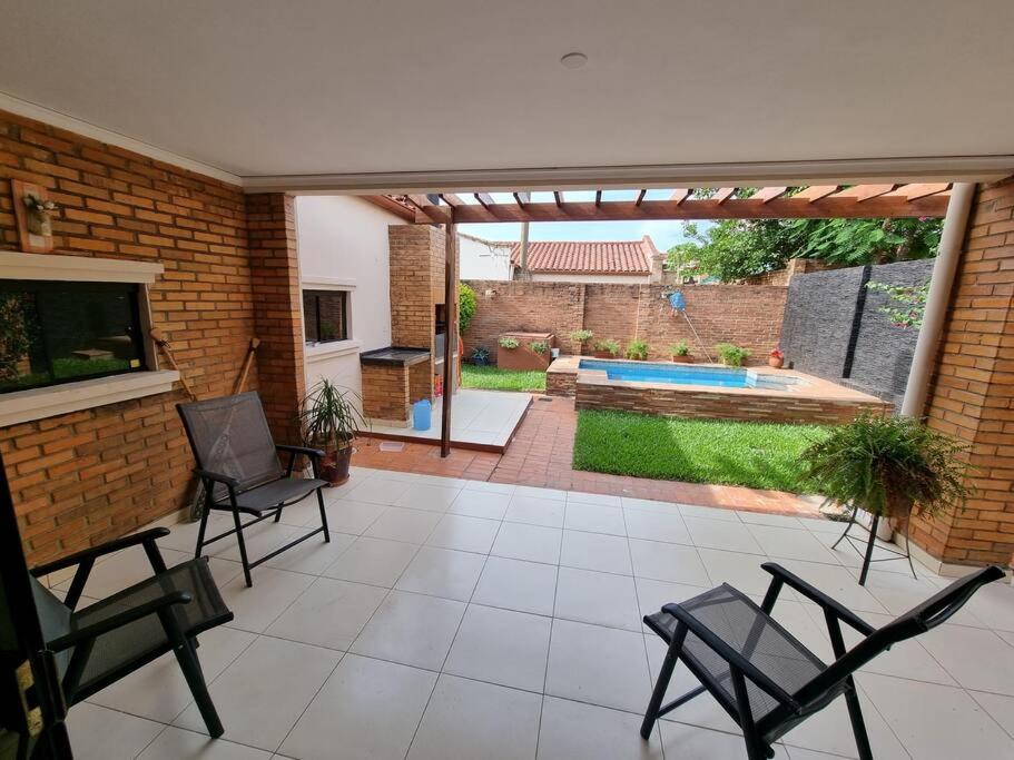a patio with two chairs and a swimming pool at Casa en condominio a 3 minutos del Aeropuerto in Luque
