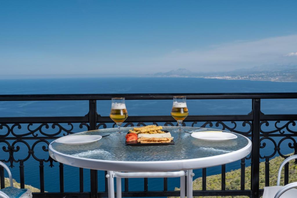 una mesa con 2 copas de vino y comida en el balcón en Galani Vacation House, en Likotinaréa