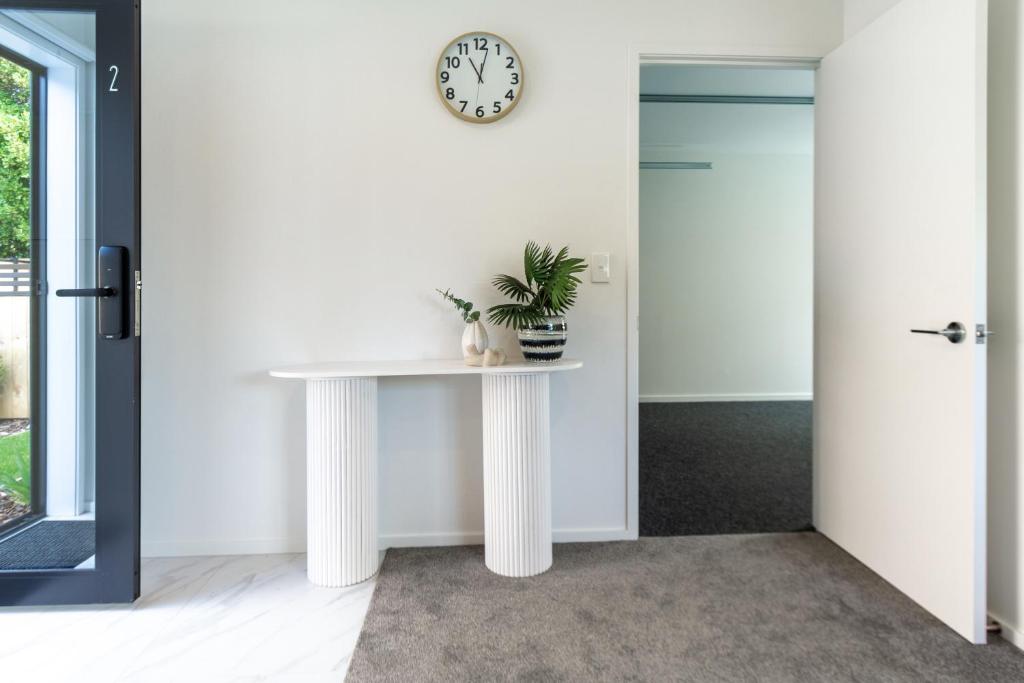 uma mesa branca num quarto com um relógio na parede em Riccarton 2 bed 1 bath w/garage em Christchurch