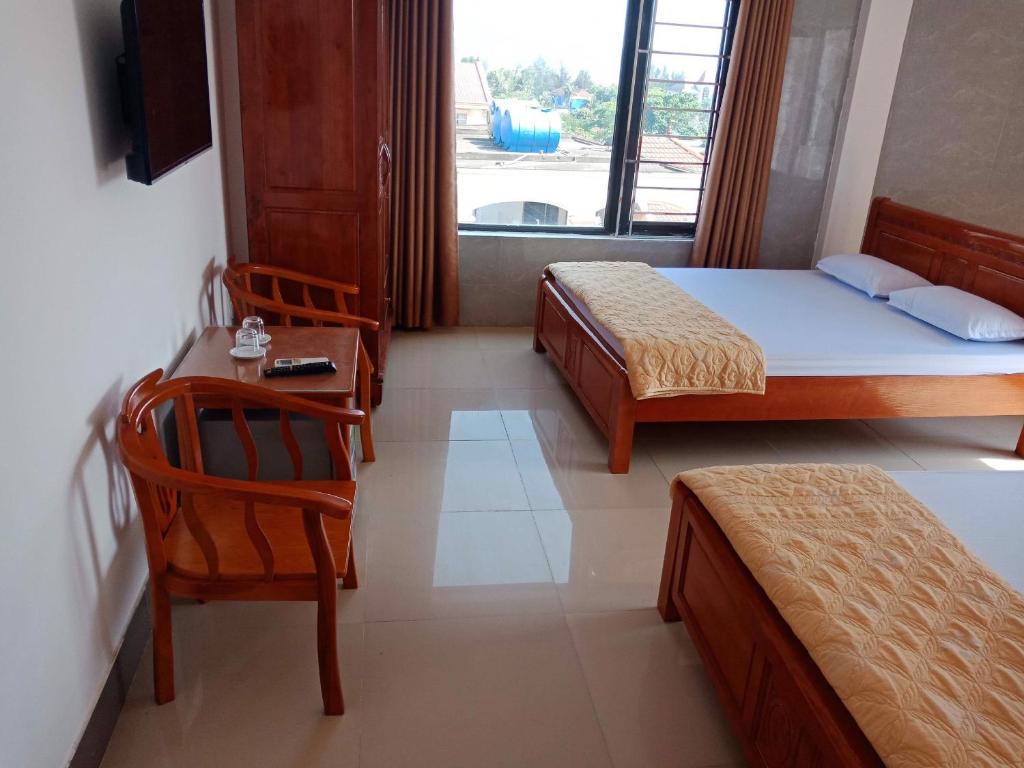 een slaapkamer met 2 bedden, een bureau en een stoel bij Hai Hoa Hotel in Cửa Lô