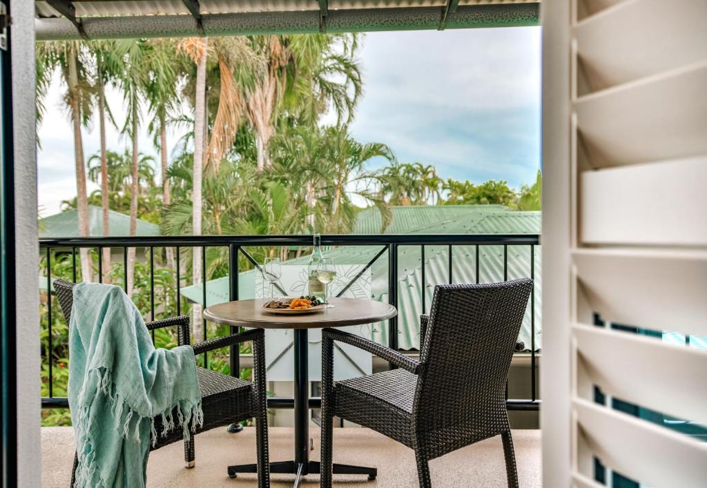 a balcony with a table and chairs and palm trees at Palms City Resort in Darwin