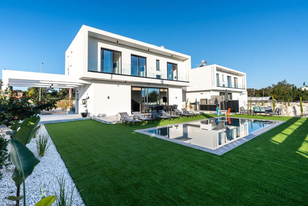 duży biały dom z dziedzińcem z basenem w obiekcie Tsiolakki Homes Luxury Villas w mieście Protaras