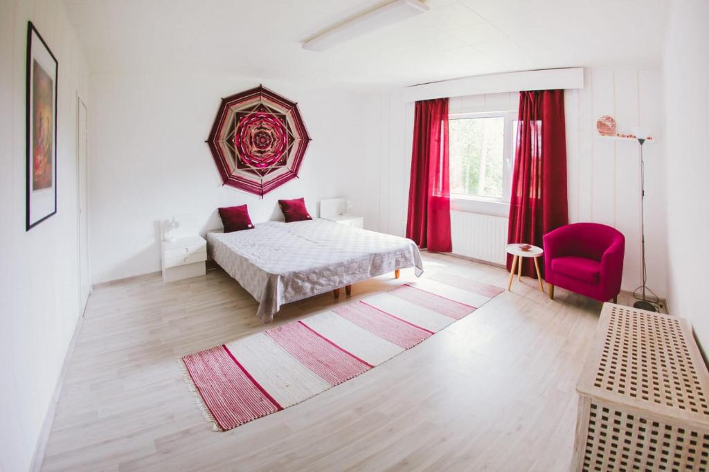 a white bedroom with a bed and a red chair at YH Lappeenranta in Lappeenranta