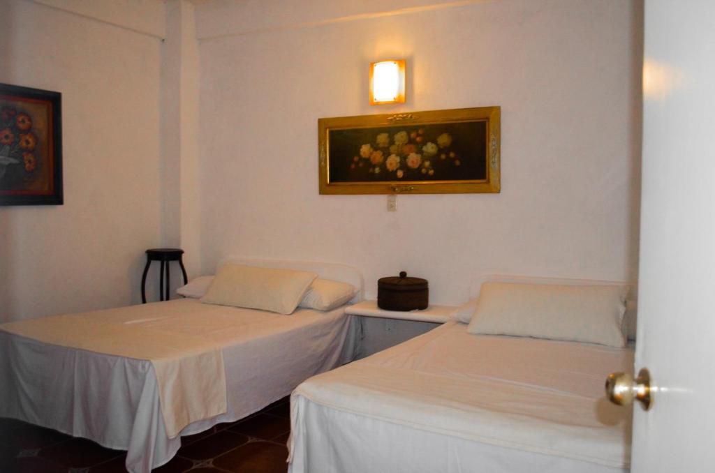 2 camas en una habitación con una foto en la pared en Posada Casa Antigua, en Tecolutla