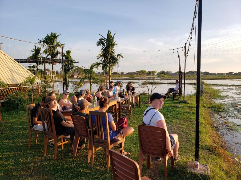 a group of people sitting at tables by a river at Onederz Siem Reap in Siem Reap