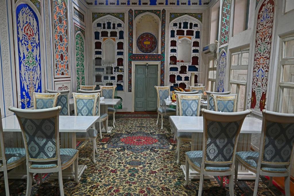 un comedor con mesas, sillas y azulejos coloridos en Grand Nodirbek Boutique Hotel, en Bukhara