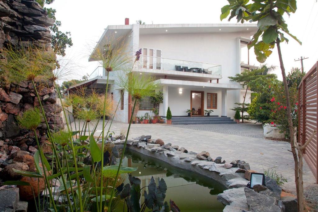 a house with a pond in front of it at StayVista at Ivory Hill Madikeri including breakfast 3 Bhk Villa in Madikeri