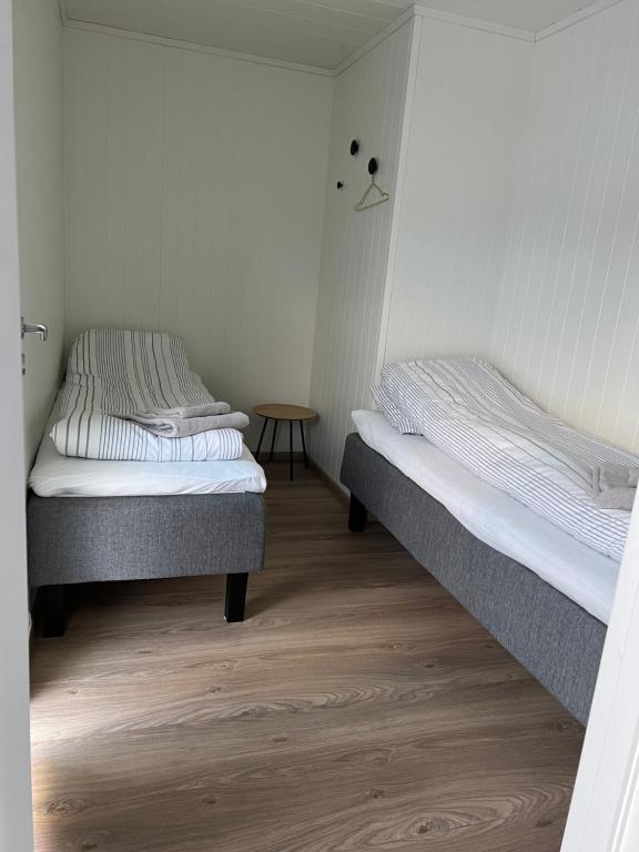 two beds in a small room with a table at Lofoten seaview in Ballstad
