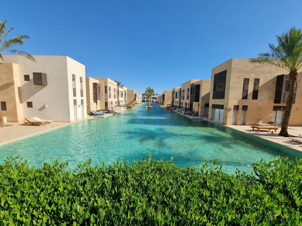 a large swimming pool between two buildings at 1 Bedroom, Pool view and 2 balconies, Scarab Club in Hurghada