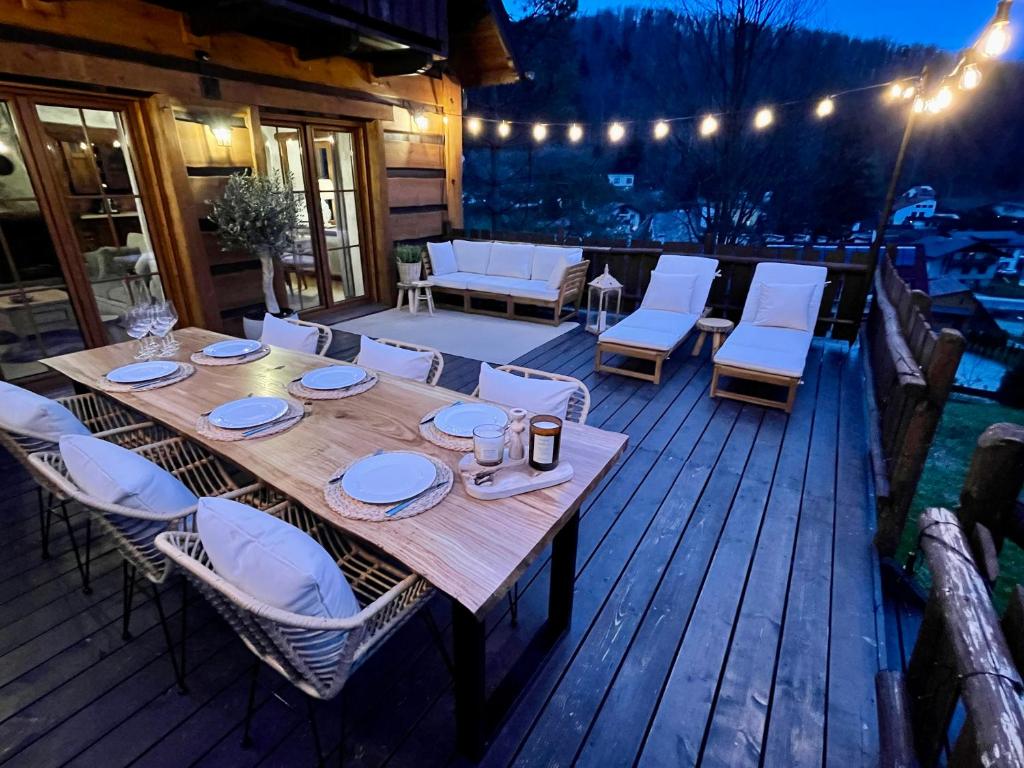 einen Holztisch und Stühle auf einer Terrasse in der Nacht in der Unterkunft Domek na Cuplu - opcjonalnie balia jacuzzi in Szczyrk