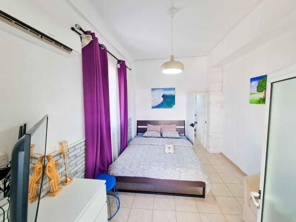 1 dormitorio con 1 cama con cortinas moradas en Aladdin's Hostel en Lárnaca