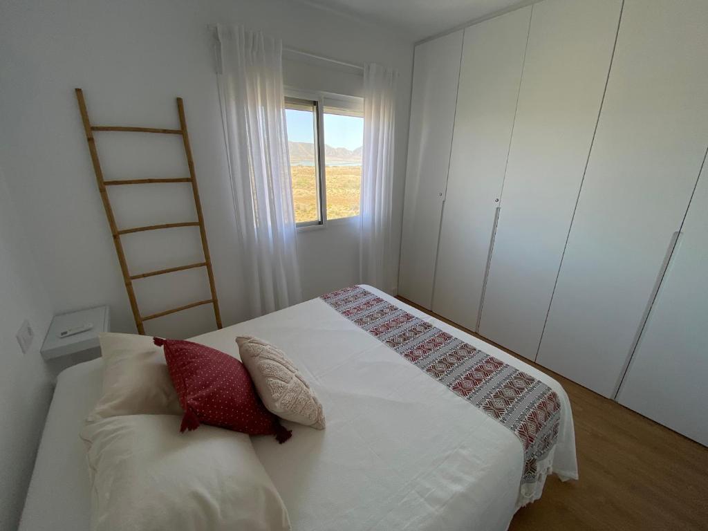 1 dormitorio con 1 cama con 2 almohadas y ventana en Tu casa en El Cabo, en Cabo de Gata