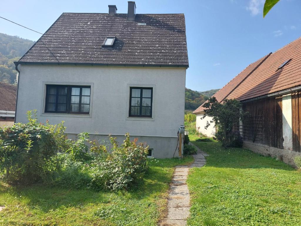 a white house with a black roof and a yard at Ferienhaus in der Wachau in Rossatzbach