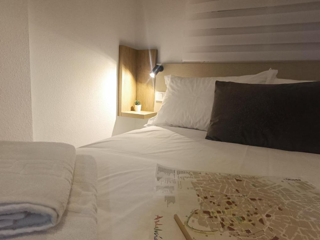 a bedroom with a white bed with a black pillow at ALOJAMIENTO VIVAL PINEDA in Baeza