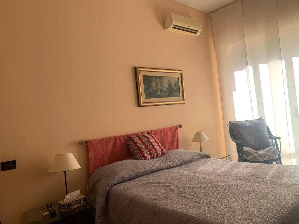 een slaapkamer met een bed en een stoel naast een raam bij La casa di Miretta in Chieti