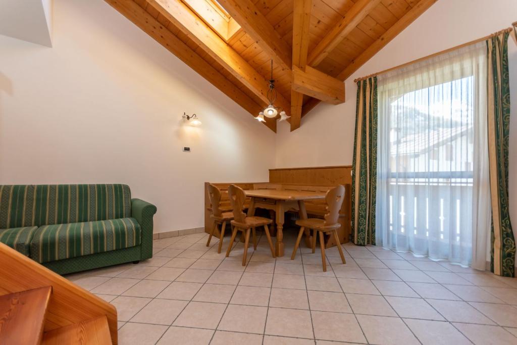 sala de estar con mesa y sofá verde en Appartamenti Villa Elisa, en Falcade