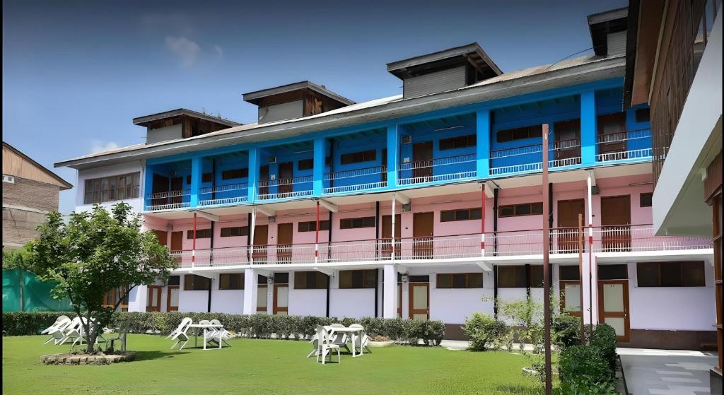 a pink and blue building with white chairs in a yard at hotel new sahil in Srinagar