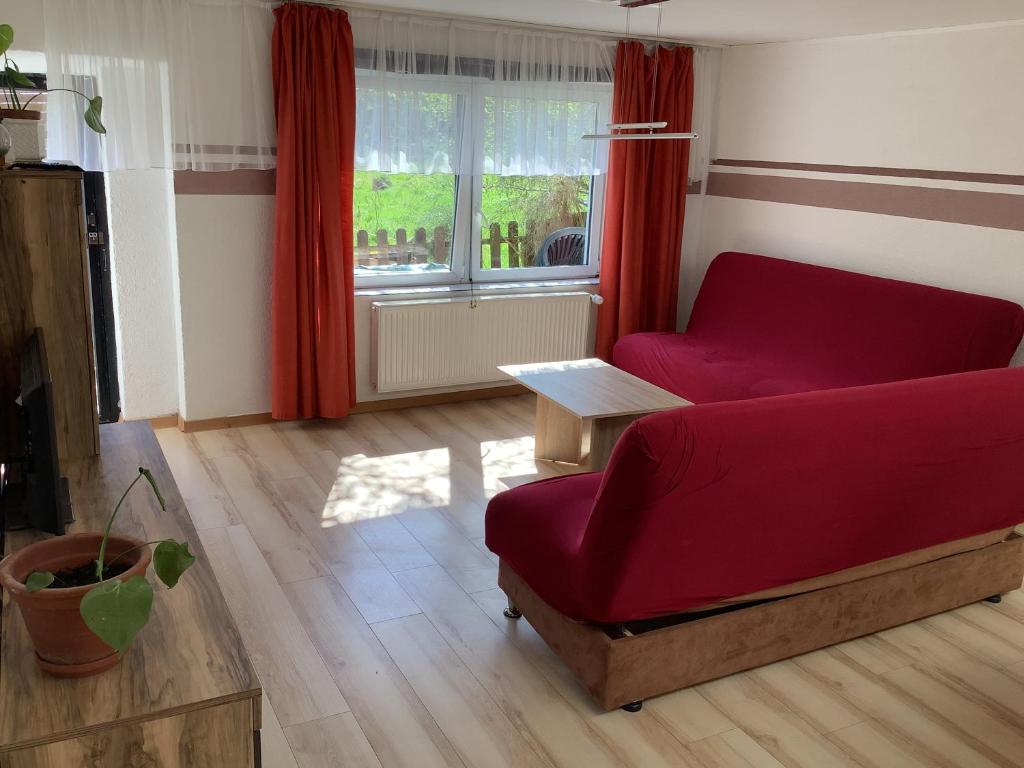 クックスハーフェンにあるApartments In Cuxhaven-Döseのリビングルーム(赤いソファ、テーブル付)