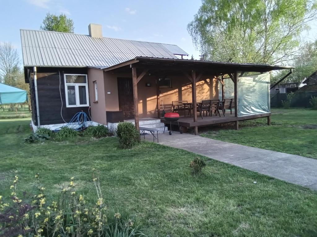 a house with a covered deck with a table and chairs at domek u Kazi in Sadowne