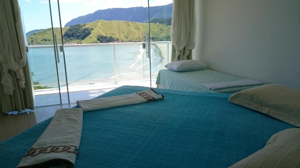 2 camas en una habitación con vistas al océano en Panoramica Residencial en Barequeçaba