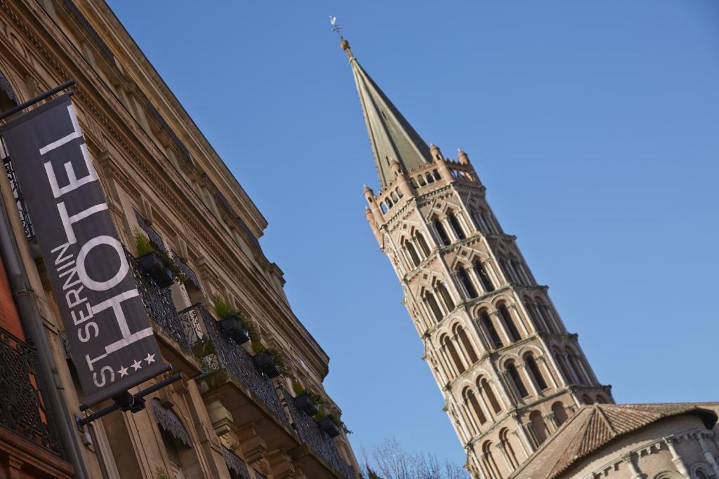 um edifício alto com uma torre de relógio ao fundo em Hôtel St Sernin em Toulouse