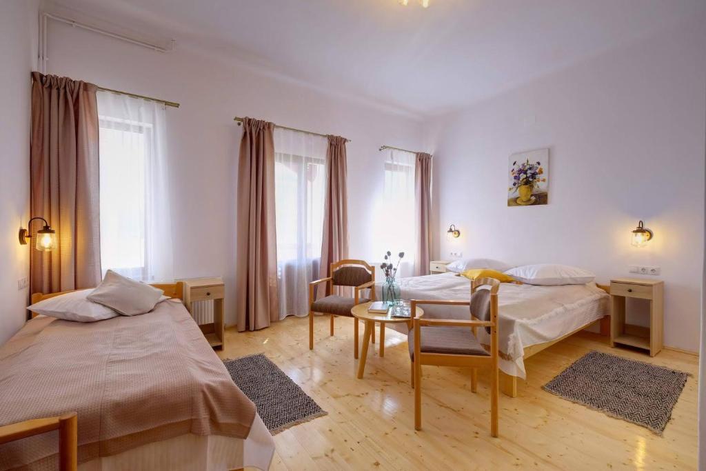 Cette chambre comprend 2 lits et une table. dans l'établissement Elimheim, à Cisnădioara