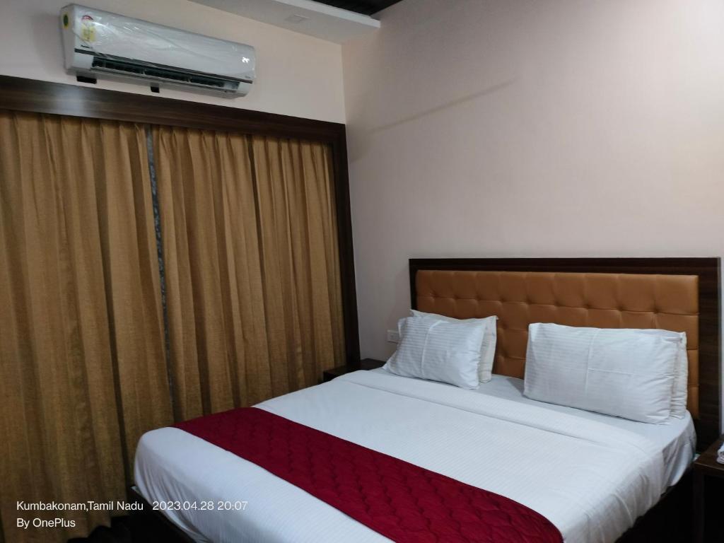 a bedroom with a large bed with avertisementatronatronstrationstrationstrationstrationstration at Sivamurugan Hotels in Kumbakonam