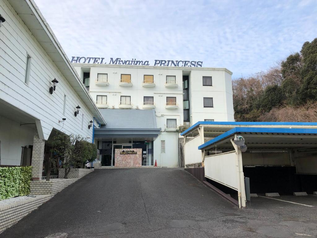 un estacionamiento vacío frente a un edificio blanco en 宮島プリンセス en Ōno