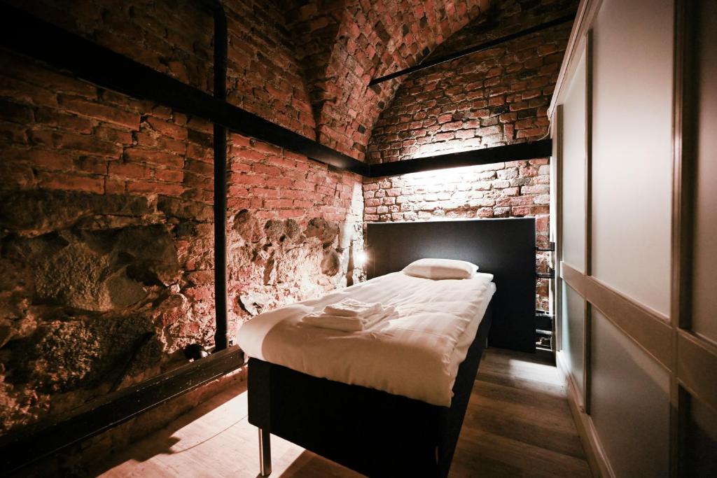 Old Town Stay Hostel في ستوكهولم: غرفة نوم بسرير في جدار من الطوب