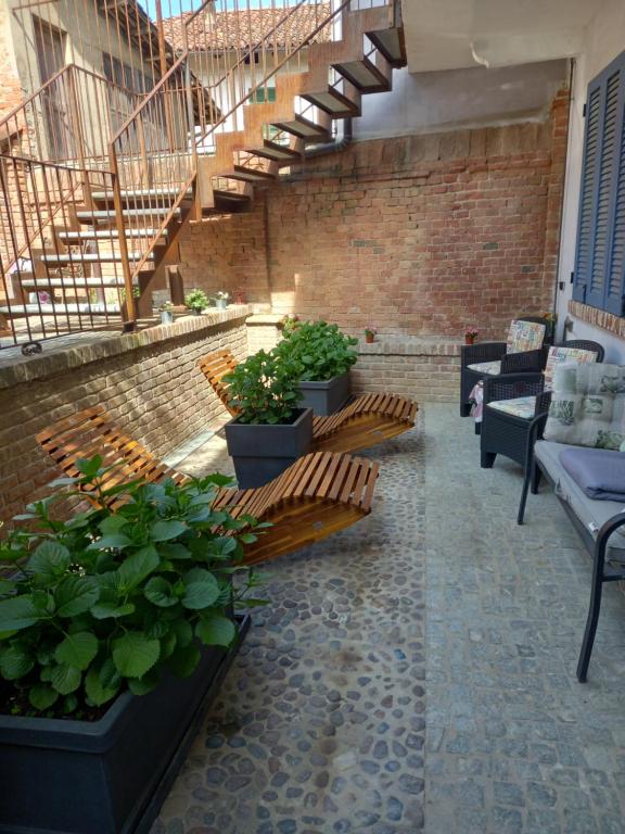 une terrasse avec bancs, plantes en pot et escaliers dans l'établissement L'ANGOLO RELAX, à La Morra
