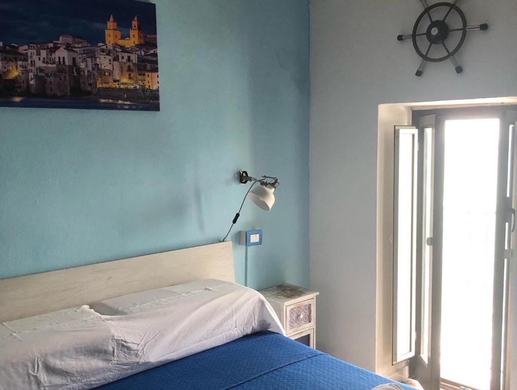 - une chambre avec un lit, une lampe et une fenêtre dans l'établissement La Casetta sul mare di Cefalù, à Cefalù