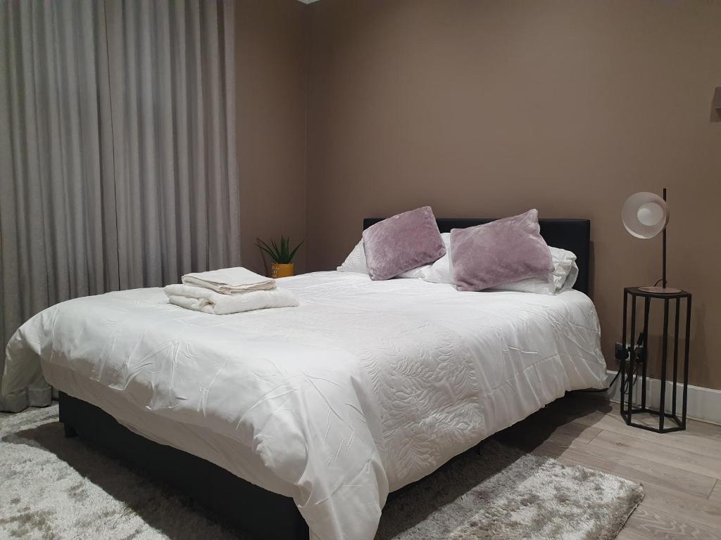 una camera da letto con un grande letto con lenzuola bianche e cuscini viola di The Westcliff Room a Southend-on-Sea