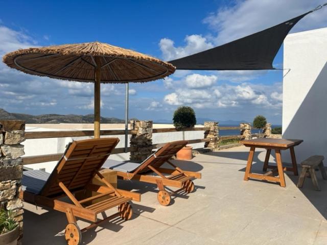 2 Stühle, ein Tisch und ein Sonnenschirm auf einer Terrasse in der Unterkunft Deja blue villa 2 in Agios Georgios