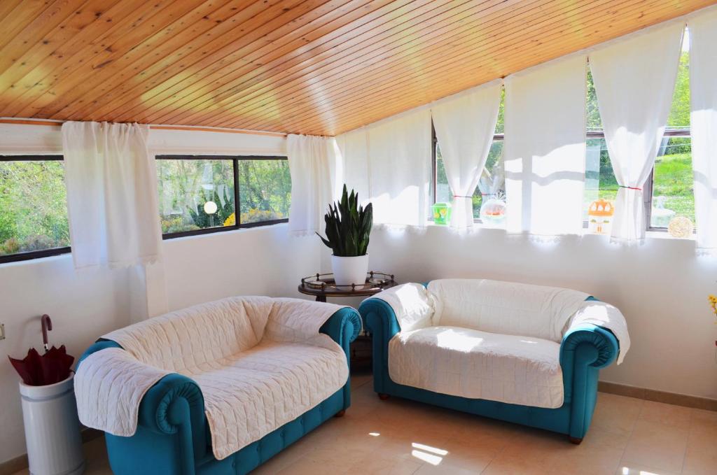 Duas cadeiras e um sofá num quarto com janelas em La Casa del Mulino em Fossombrone
