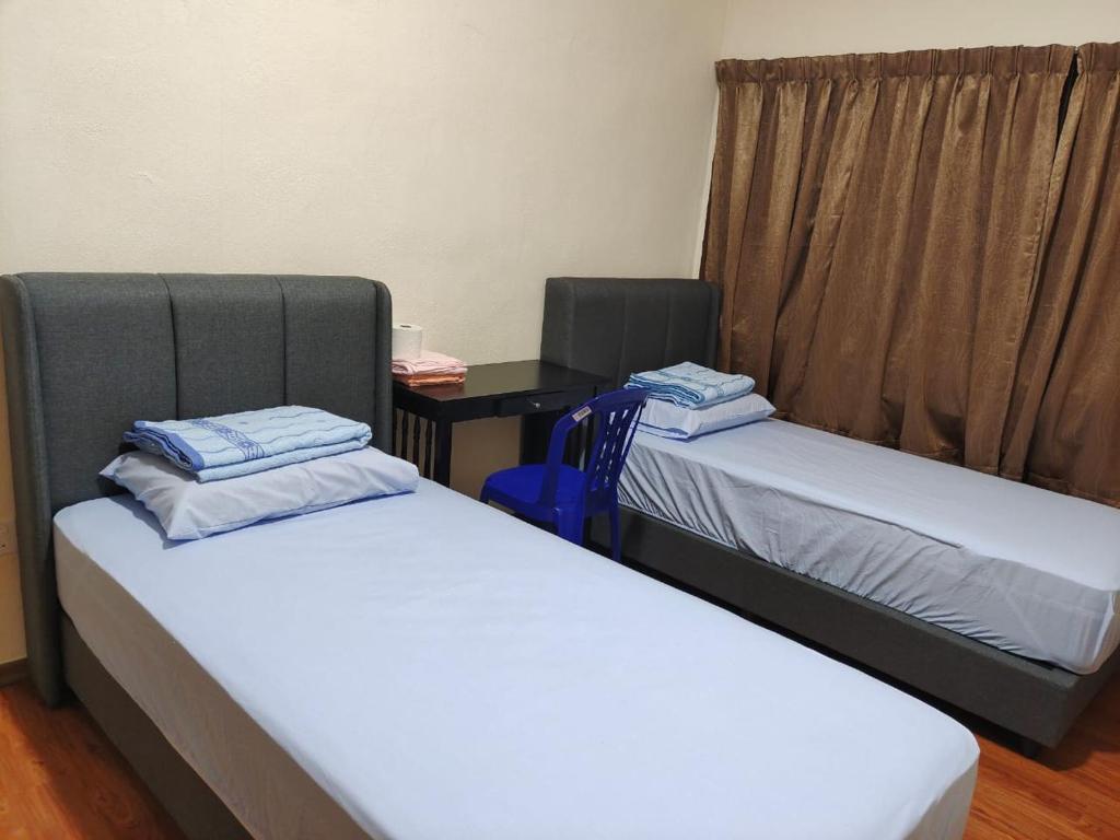 two twin beds in a room with a desk at clp perai homestay near Sri Muniswarar Temple 2 in Perai