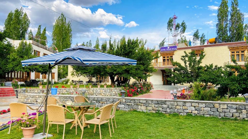 a table and chairs with an umbrella in a yard at hotel palam hills in Leh